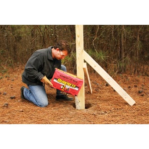 Setting a wooden fence post with fast setting concrete mix poured dry into the hole