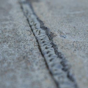 Textured sealant bead filling a concrete crack, blending with the surrounding surface