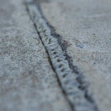 Textured sealant bead filling a concrete crack, blending with the surrounding surface