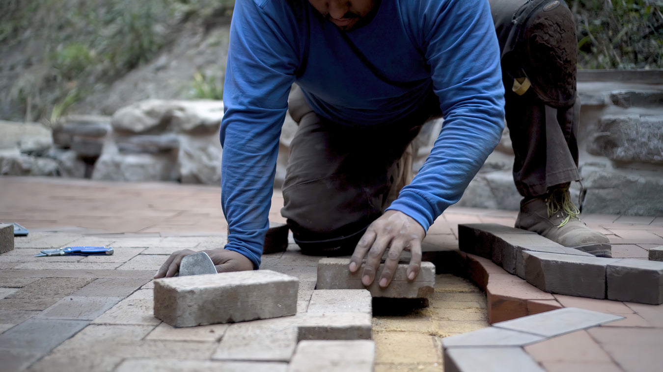 man laying pavers to be filled polymeric sand