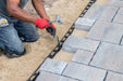 Driving a steel spike through SEK paver edge restraint into the compacted base