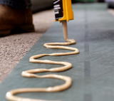 Turf adhesive applied in an S bead along seam tape with an applicator gun